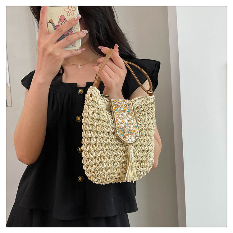 Beige straw crochet crossbody bag with beaded flap, long tassel, and braided strap