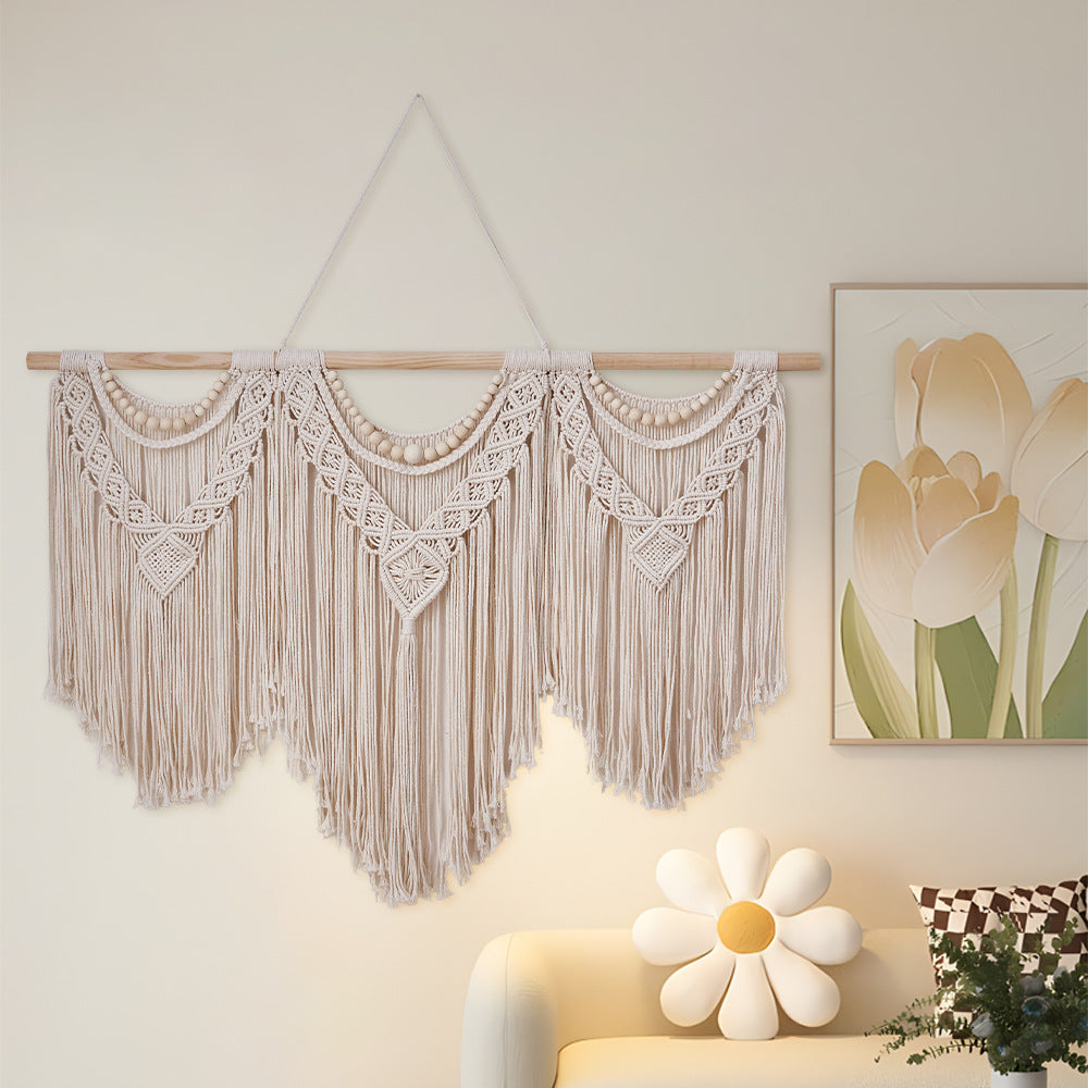 Cream cotton macrame wall hanging with wooden dowel, scalloped macrame panels, and long fringe